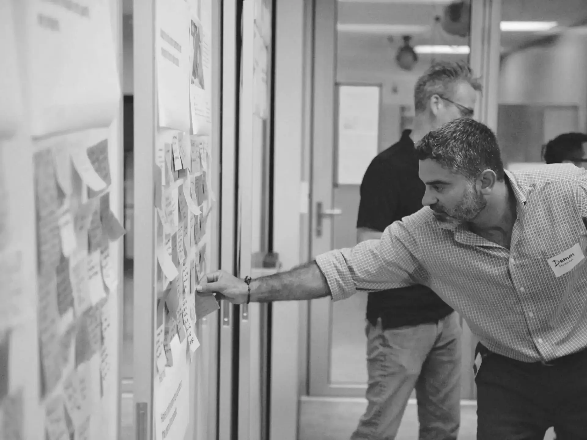 A workshop participant adding a sticky note to a wall of research boards